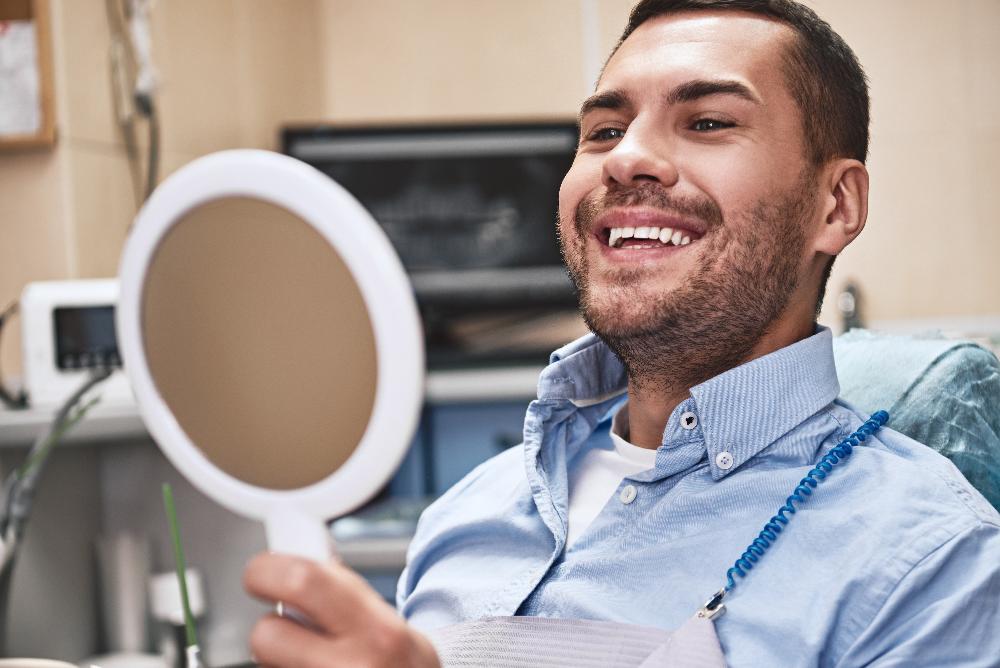 man looking at dental mirror after cleaning in Havertown